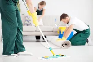 Three People cleaning a room with sponges and mop